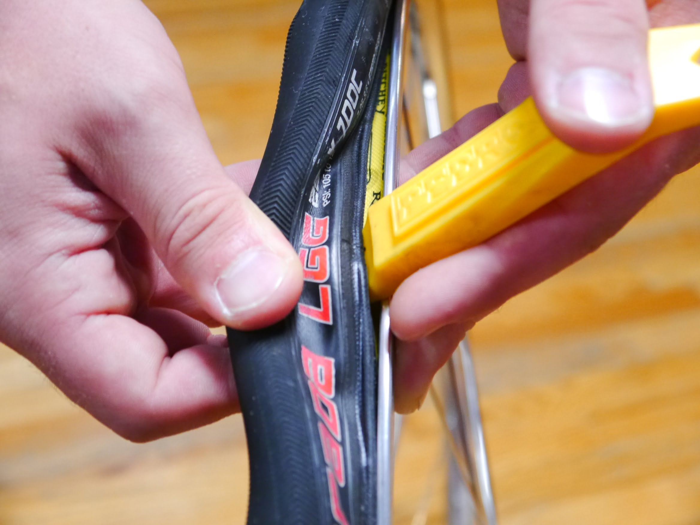 Započinjanje skidanja gume pomoću alata: Pažljivo se umetne između spoljne gume i felne, pazeći pritom da se ne pričkine unutrašnja guma.